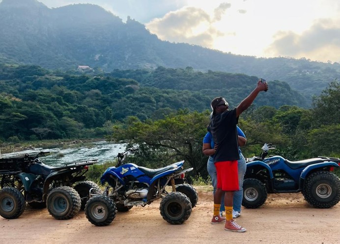 Quad bikers on a dirt track with mountains in the background